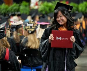 Maryville student smiling holding up diploma at graduation